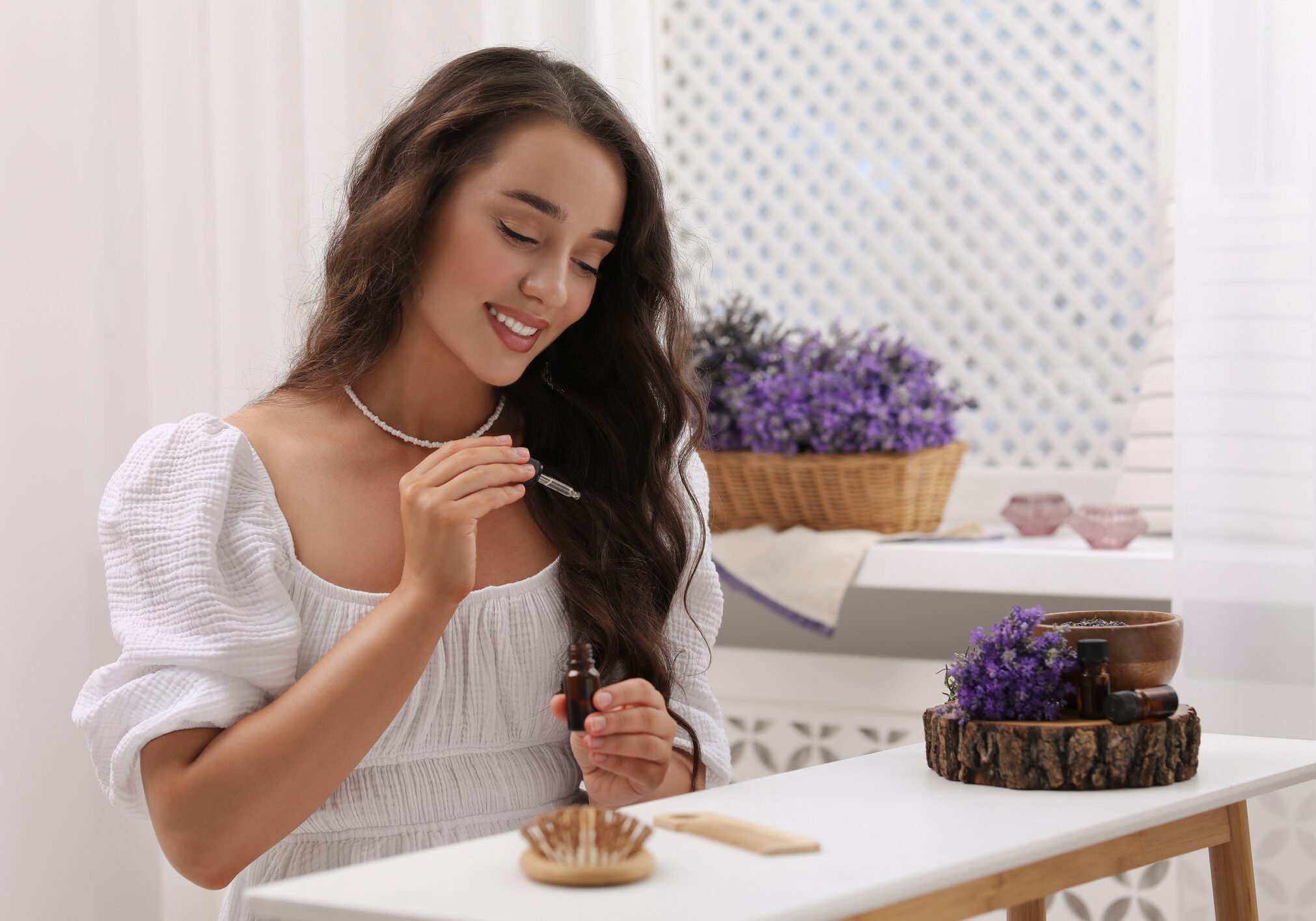 Woman applying essential oil to hairbrush.